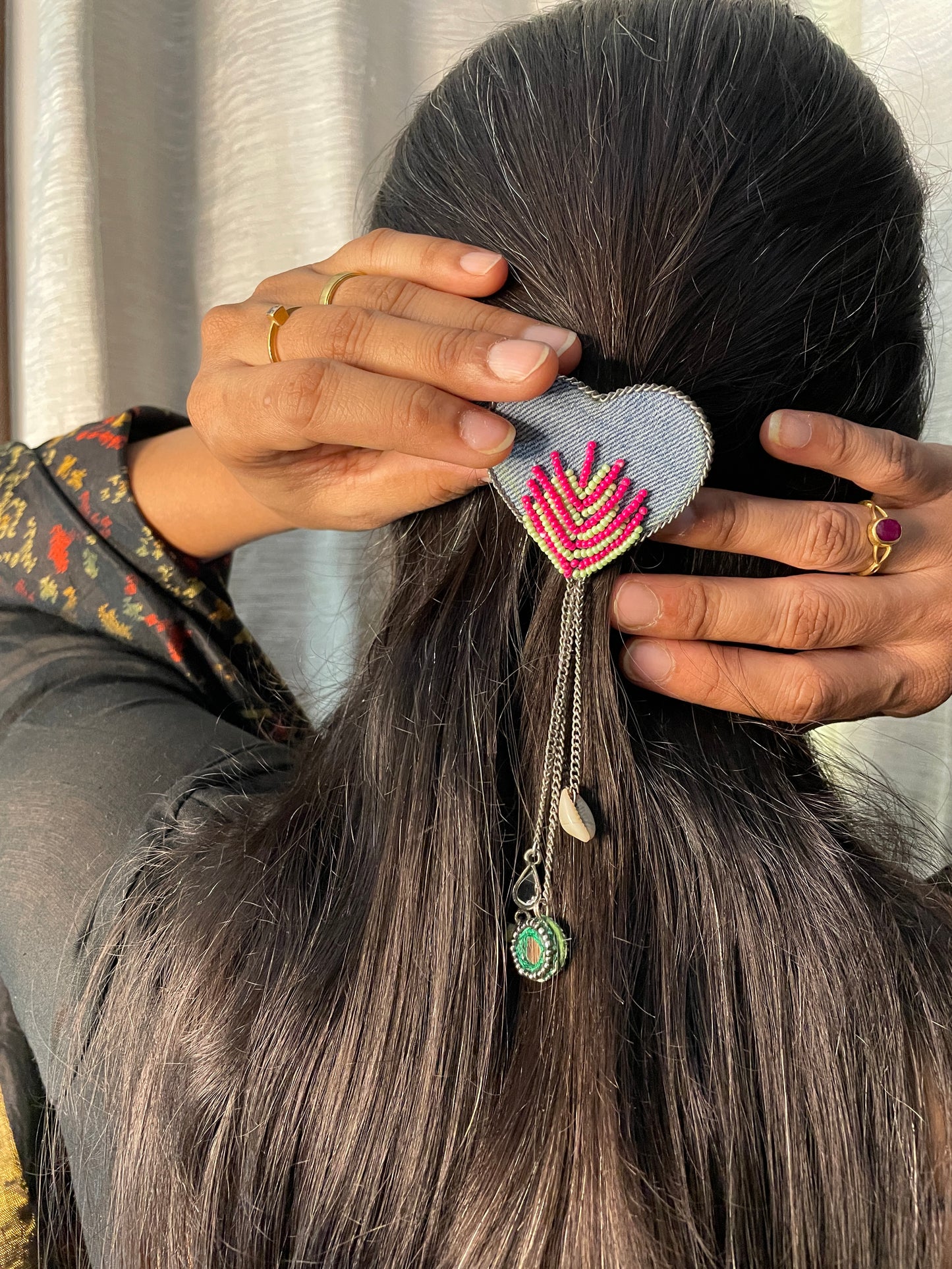 Person styling hair with decorative hair tie and accessories.