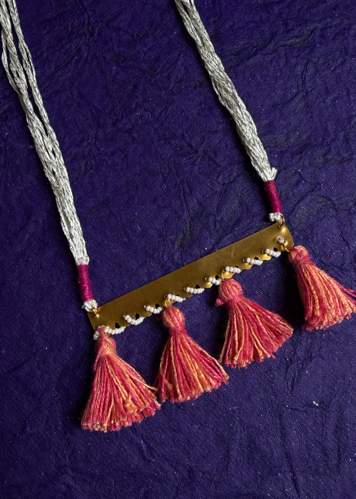 Necklace with pink tassels on a textured purple background